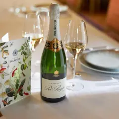 Eine Flasche Pol Roger Champagner steht bereit, daneben ein Glas und eine Speisekarte mit floralem Muster.