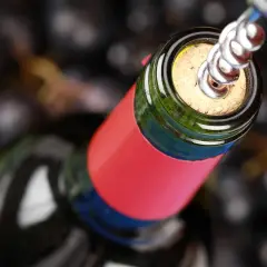 Ein Korkenzieher öffnet eine Flasche Wein, bereit für den Genuss. Ein Glas Wein am Tag hält den Arzt fern.