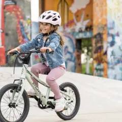 Uśmiechnięta dziewczynka w kasku jedzie na rowerze 16 cali, idealnym dla 4 latka.