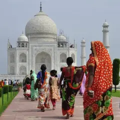 Tłum turystów, w tym kobiety w barwnych sari, zwiedza Taj Mahal. Zastanawiasz się, ile kosztuje wiza do Indii, by zobaczyć to cudo?