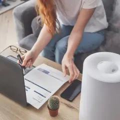 Donna lavora al computer con umidificatore attivo. Soluzione per sacchetti anti umidità fai da te.