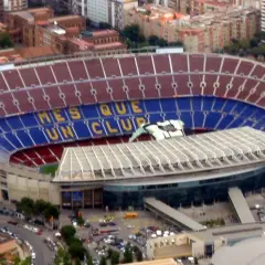 Camp Nou, z imponującą pojemnością, wita kibiców. Na trybunach widnieje napis "Més que un club".