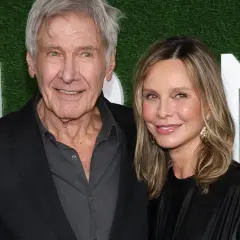 Harrison Ford z żoną Calistą Flockhart na tle zielonej ściany z białymi literami.