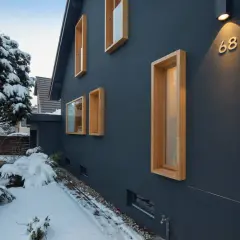 Modernes Haus mit Holzfenstern im Schnee. Ein Architekt hat hier mit klaren Linien und Kontrasten gebaut.