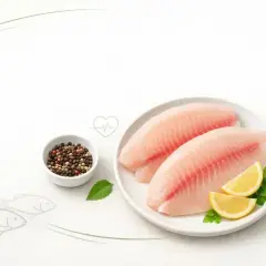 Dwa filety ryby tilapia na talerzu z cytryną i natką pietruszki. Obok miseczka z pieprzem. Czy ryba tilapia jest zdrowa?
