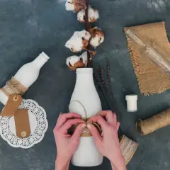 Ręce wiążą sznurkiem butelkę, tworząc ozdobę. Idealne pomysły, co można zrobić na Dzień Chłopaka DIY.
