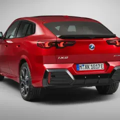Czerwone BMW iX2 z napisem "XDrive30" na klapie bagażnika, z tyłu widoczne są lampy LED i tablica rejestracyjna.