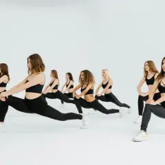 Grupo de mujeres realizando estocadas, parte de **15 ejercicios de calentamiento** para preparar el cuerpo.