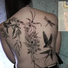 Rücken-Tattoo mit Schwalben, Blumen und Libelle. Die filigranen Linien und die detailreichen Schriften machen dieses Kunstwerk einzigartig.