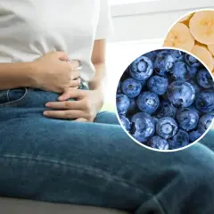 Osoba z bólem brzucha, wskazująca na potencjalne problemy z trawieniem. W tle jagody i plasterki banana – naturalne sposoby na biegunkę.