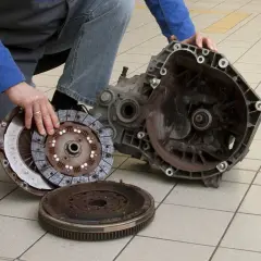 Mechanik pokazuje rozłożony zestaw sprzęgła i skrzynię biegów. Uszkodzony wysprzęglik objawy mogą być różne, ale ten element jest kluczowy.