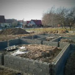 Budowa fundamentów domu w trakcie. Widać zbrojenie i bloczki betonowe, przygotowywane pod izolację poziomą fundamentów.