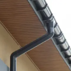 Szary rynna i rura spustowa, podbitka drewniana i nadbitka dachowa tworzą estetyczny system odprowadzania wody.