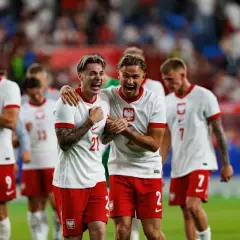 Piłkarze Polski świętują zwycięstwo nad Finlandią. Dwóch zawodników w białych koszulkach z orłem na piersiach, z szeroko otwartymi ustami, cieszy się z sukcesu.
