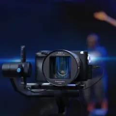 Kamera z obiektywem anamorficznym 1.33X na stabilizatorze, gotowa do uchwycenia dynamicznej sceny z ludźmi w tle.
