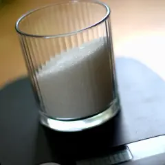 Szklanka z cukrem na wadze kuchennej.