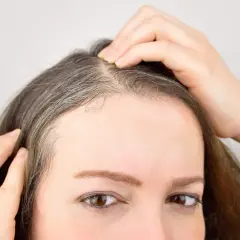Mujer revisando sus canas, pensando en un baño de color para canas.