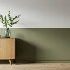 Eine zweifarbige Wand in Weiß und Olivgrün, akzentuiert durch ein Holzsideboard mit Vase und Büchern.
