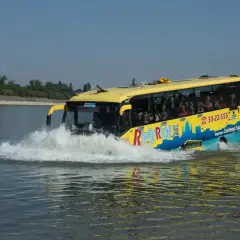 Żółty autobus "River Ride" wjeżdża do wody, tworząc fontannę. To niezwykła atrakcja turystyczna, która zabiera pasażerów na wycieczkę po Dunaju w Budapeszcie.