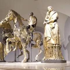 Bronzi dorati di Pergola: un cavaliere su un cavallo, una figura femminile e altre statue antiche.