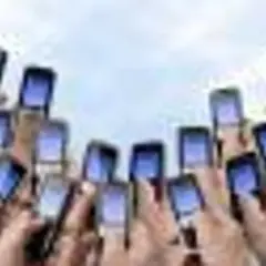 Ręce trzymają telefony komórkowe, gotowe do wysłania pustego SMS-a na loterię.
