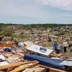 Ludzie przeszukują ruiny po tornadzie w jednym z miasteczek w stanach w USA. Wszędzie widać zniszczone domy i porozrzucane przedmioty.
