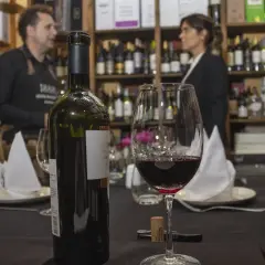 Butelka i kieliszek wina gruzińskiego, w tle sprzedawca w sklepie z winami w Tbilisi.