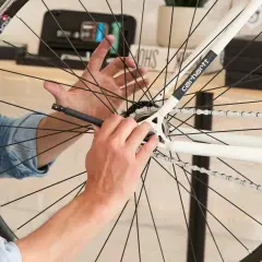 Mężczyzna próbuje zdjąć zębatkę z tylnego koła roweru, używając narzędzia.