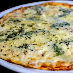 Eine köstliche quattro formaggi pizza mit geschmolzenem Käse und Kräutern, serviert auf einem weißen Teller.