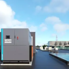 Enfriadora de aire-agua Atlas Copco TCA-215AP en una azotea, con edificios y cielo azul al fondo.
