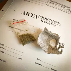 Mała torebka z suszem i grudka substancji w folii aluminiowej na dokumentach śledczych.