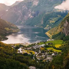 Malowniczy fiord w Norwegii, z zielonymi zboczami gór, wodospadami i małą wioską. Klimat tego miejsca sprzyja podziwianiu natury.