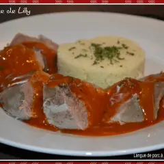 Langue de porc en sauce tomate, servie avec une portion de semoule garnie d'herbes. Un plat savoureux de "la cuisine de Lilly".