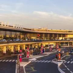Orly Ouest, jedno z lotnisk w Paryżu, tętni życiem. Samochody i autokary czekają na pasażerów przy nowoczesnym terminalu.
