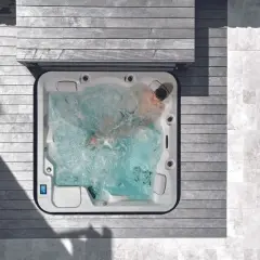 Un homme profite d'un traitement spa relaxant dans un jacuzzi bouillonnant, entouré de bois et de pierre.