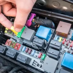 Mano retirando un fusible amarillo de la caja de fusibles del coche. Averiguar cuanto cuesta cambiar un fusible del coche es fácil con esta imagen.