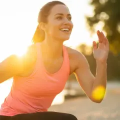Mujer sonriente corriendo al atardecer, un secreto para como mantenerse joven es la actividad física y disfrutar del sol.
