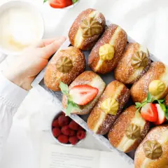 Frisch gebackene Faschingskrapfen mit Puderzucker, Erdbeeren und einer Tasse Kaffee. Ein Genuss zum Fasching!