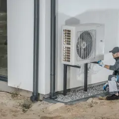 Tecnico che installa una pompa di calore esterna, un sistema efficiente per riscaldare e raffreddare la casa.