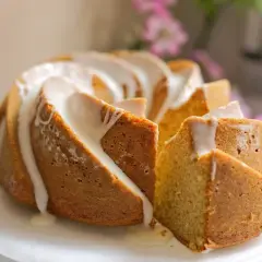 Bizcocho de yogur Thermomix con glaseado blanco, una porción cortada revela su interior esponjoso.