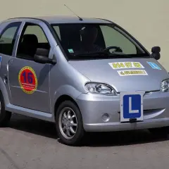Srebrny samochód z literą "L" na masce i drzwiach, gotowy do nauki jazdy. Idealny do zdobycia prawa jazdy B1.