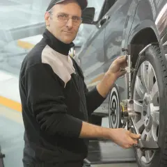 Mekaniker justerar hjulinställningen på en bil. Han ser till att allt är perfekt för att serva bilen.