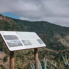 Panel informativo en el mirador de Carboneras, con vistas a un valle montañoso cubierto de vegetación.
