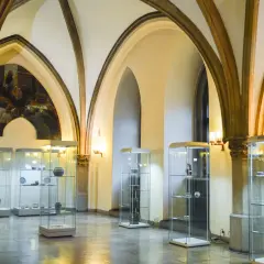 Wnętrze muzeum sztuki mieszczańskiej we Wrocławiu. W salach z arkadowymi sklepieniami wyeksponowano ceramikę i naczynia w szklanych gablotach.