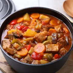 Gęsty, aromatyczny gulasz z warzywami: mięso, ziemniaki, marchewka, papryka i cukinia w sosie pomidorowym.