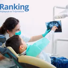Dentystka w masce pokazuje dziecku zdjęcie rentgenowskie zębów.