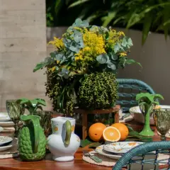A vibrant tablescape with citrus-themed plates, green pitchers, and a lush floral arrangement. This modern everyday dining table decor evokes a fresh, summery feel.