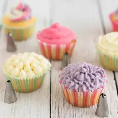 Bunte Cupcakes mit verschiedenen **cupcake topping** Mustern, umgeben von Spritztüllen.