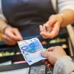 Une main tend un billet de 20 euros pour une saisie avoir espèces. Une caisse enregistreuse est visible en arrière-plan.
