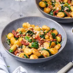 Pyszne gnocchi ze szpinakiem i suszonymi pomidorami, posypane parmezanem i orzeszkami pinii. Idealne danie na szybki obiad.